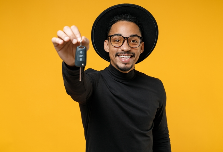 A person holding the keys to their new car against a yellow background near Anderson, Indiana