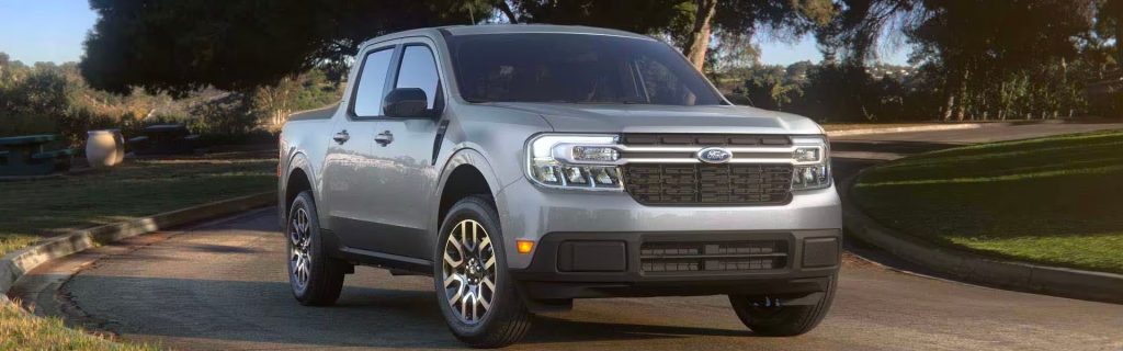 2025 silver grey Ford Maverick driving on a scenic country road in Anderson, IN