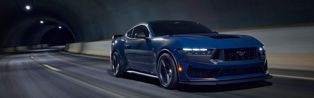 A blue Ford Mustang driving through a tunnel at night.