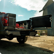 Ford F-150 with its tailgate open and tools loaded in the bed, parked beside a metal barn