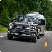 Ford F-150 towing a travel trailer on a two-lane road