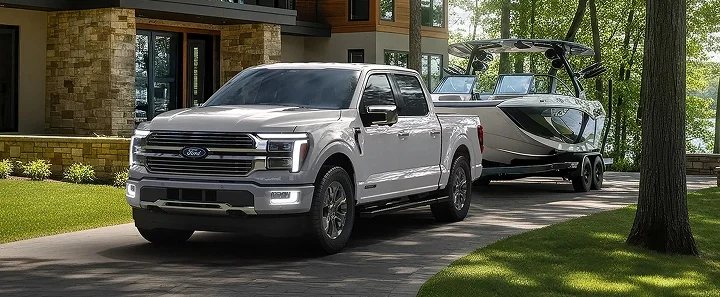 Silver Ford F-150 towing a boat past a house