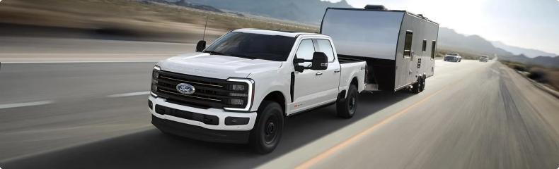White Ford Super Duty towing a travel trailer on a desert highway