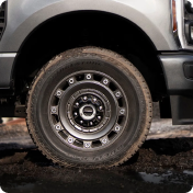 Close-up of a Ford Super Duty front wheel and tire on muddy ground
