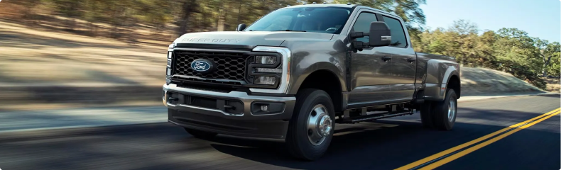 Gray Ford Super Duty dual-rear-wheel pickup driving on a two-lane road
