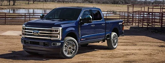Ford Super Duty Crew Cab in a top trim parked beside ranch fencing
